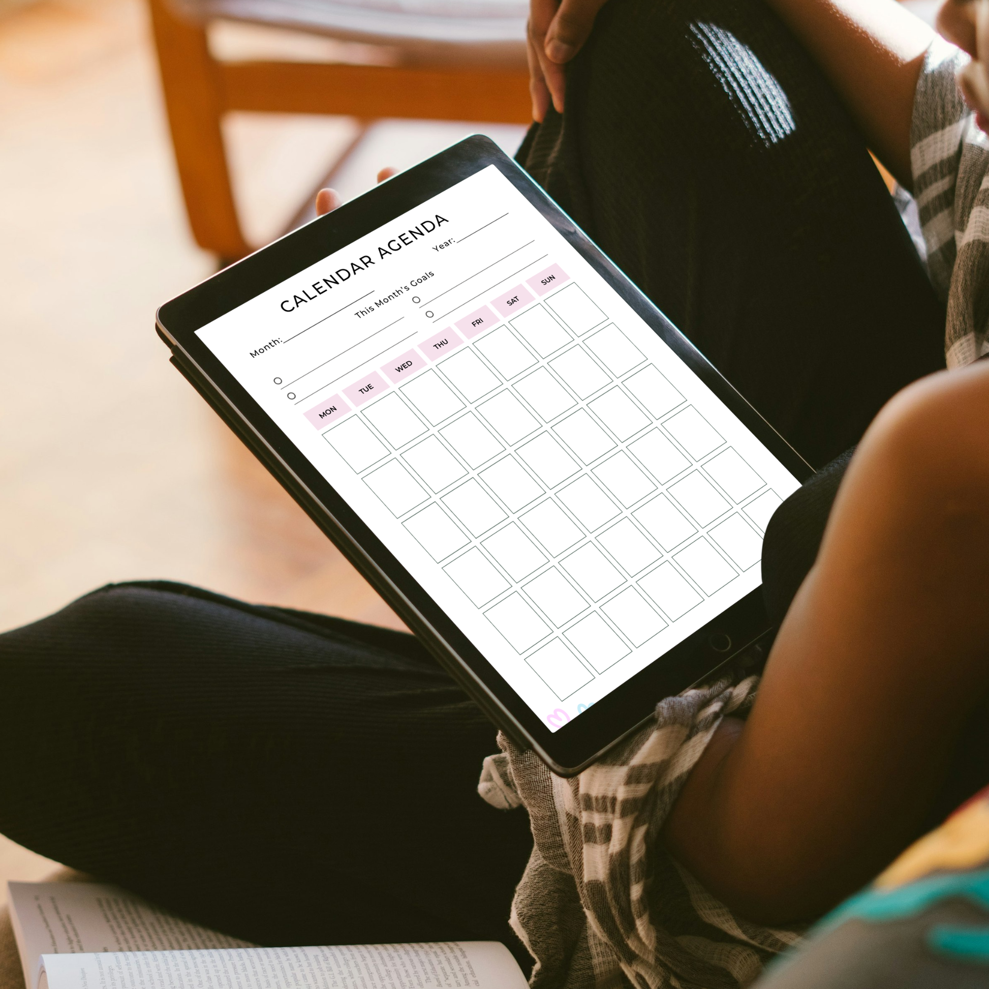Undated digital calendar agenda monthly planner PDF template shown on an iPad with a clean minimal white design and soft pink accents, featuring a month and year field, this month's goals section with four goal slots, and a full monthly calendar grid with Monday through Sunday columns — compatible with GoodNotes, Notability, Noteshelf, XODO, Samsung Notes, and Kindle Scribe.