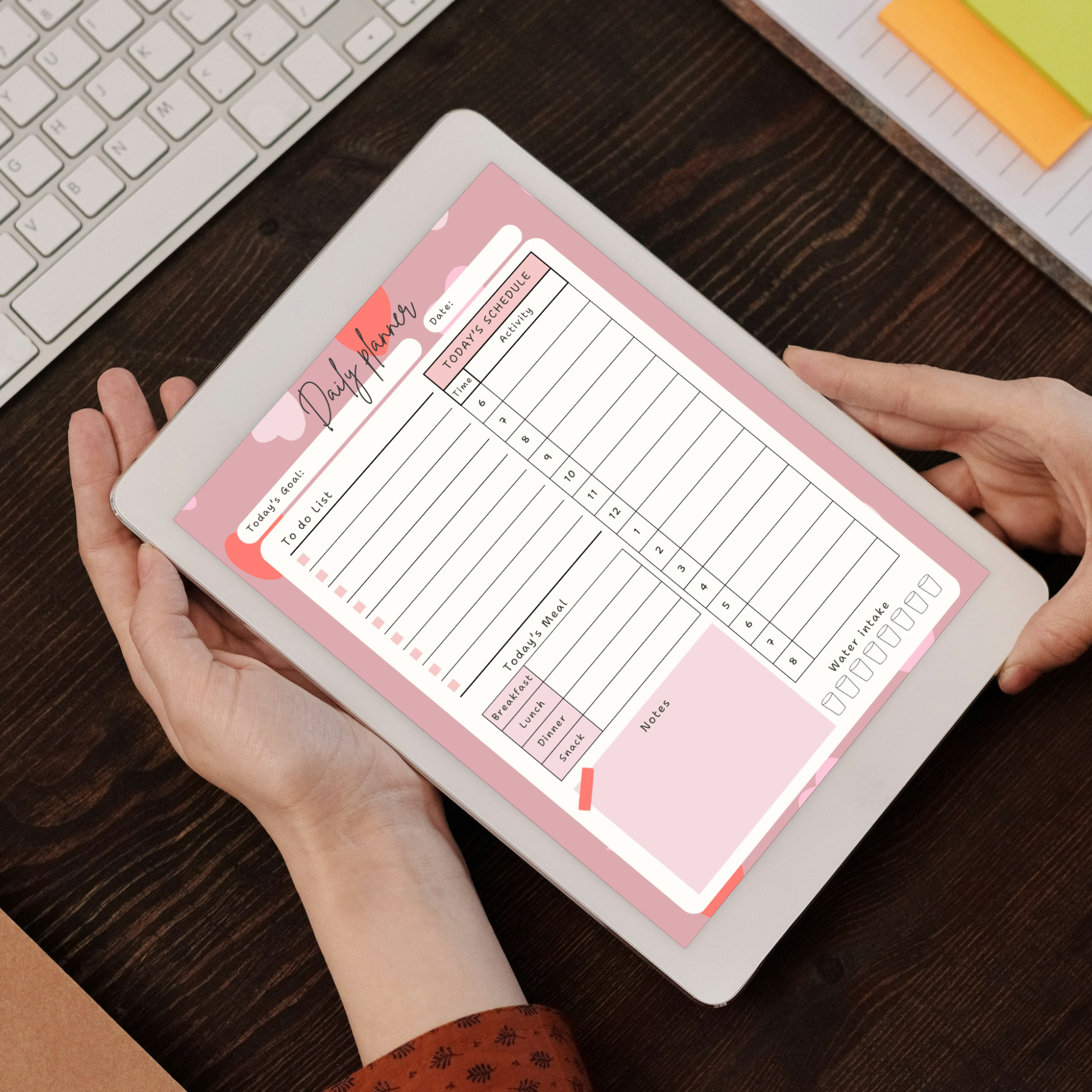 Hands holding iPad with digital daily planner PDF showing hourly schedule to-do list meal tracker and water intake tracker.