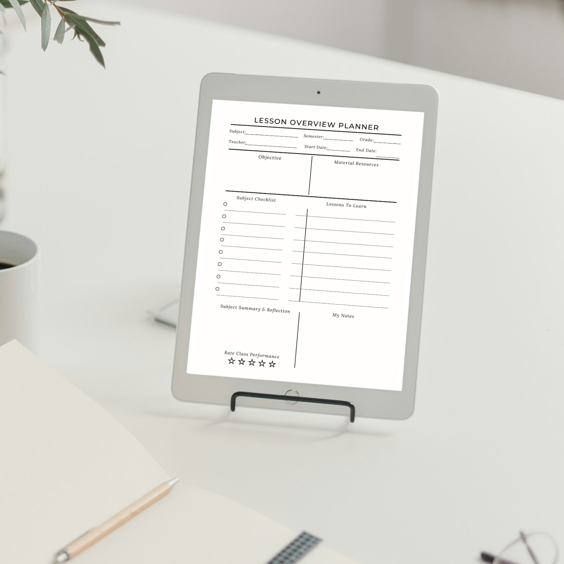 A tablet device on a small stand displaying a lesson overview planner template on a white desk with a notebook, pencil, and plant in a bright indoor setting.